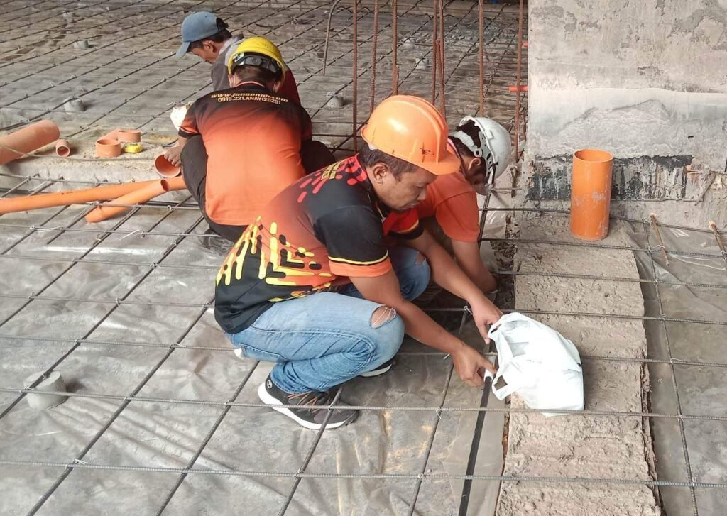 Technicians installing termite reticulation piping beneath a building foundation during construction in Boracay.